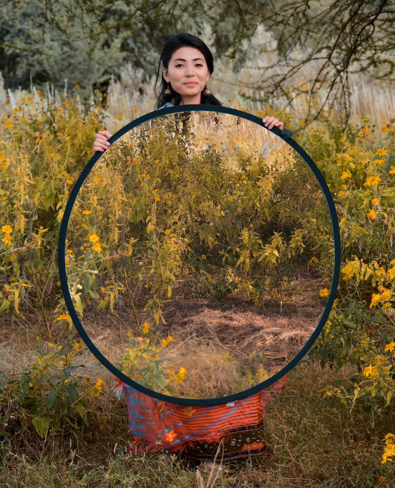 Lady in forest holding circular frame making her seem translucent.